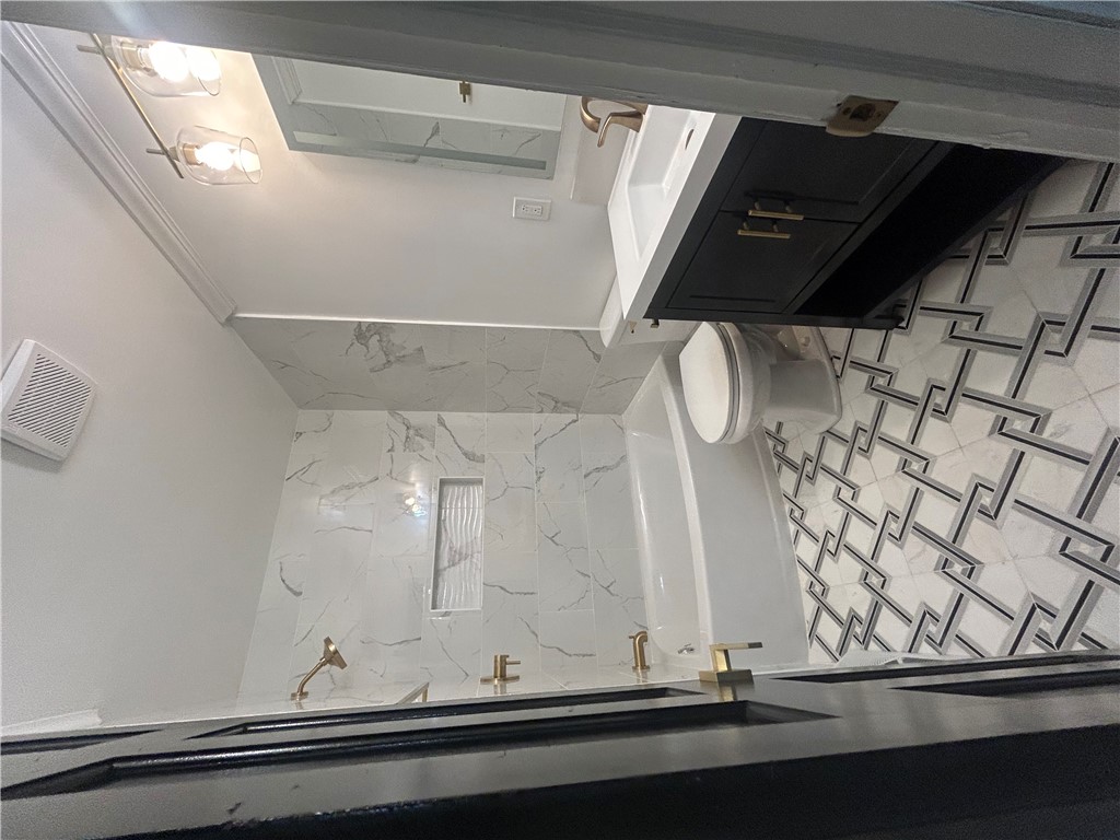 809 Paige Road Honea Path, SC 29654 - Photo 19 of 27 Geometric patterned tile flooring grounds this modern bathroom, featuring a sleek vanity and shower.