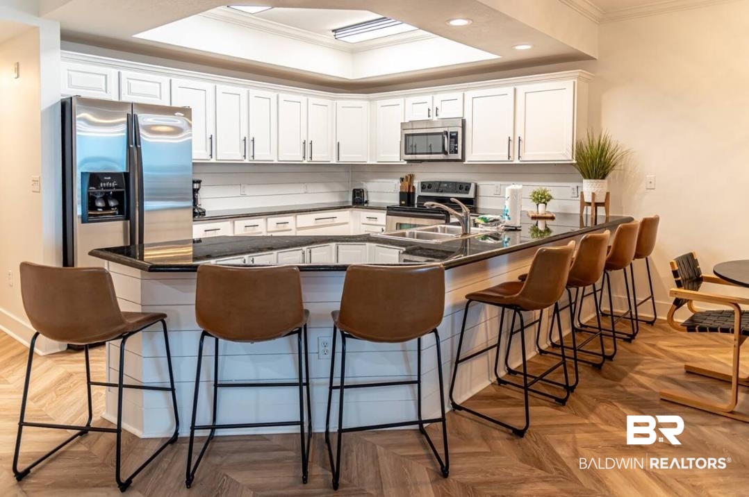 27800 Canal Road, Unit 212 Orange Beach, AL 36561 - Photo 9 of 43 Kitchen with crown molding, a breakfast bar area, white cabinetry, stainless steel appliances, and dark countertops