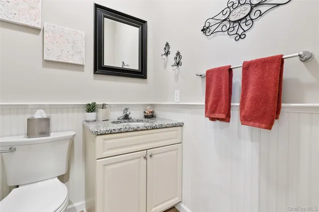 a bathroom with a granite countertop toilet sink and mirror