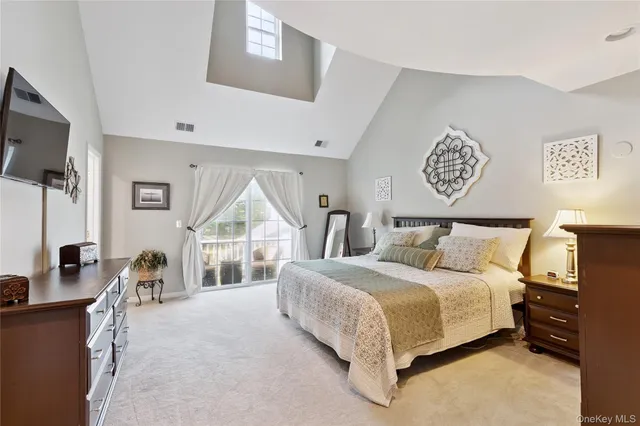 a spacious bedroom with a bed and a flat tv screen on the dresser