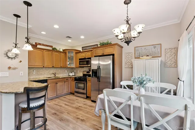 a kitchen with stainless steel appliances granite countertop a dining table chairs stove refrigerator and microwave