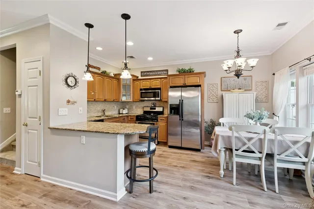 a kitchen with stainless steel appliances kitchen island granite countertop a refrigerator a stove top oven a sink dishwasher and a dining table with wooden floor