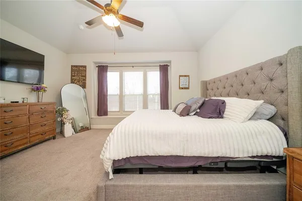 a bedroom with a bed a mirror and a flat tv screen on dresser