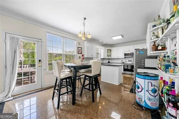 a kitchen with stainless steel appliances kitchen island granite countertop a dining table chairs sink and cabinets