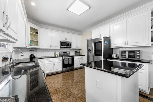 a kitchen with stainless steel appliances granite countertop a refrigerator a stove a sink dishwasher and white cabinets with wooden floor