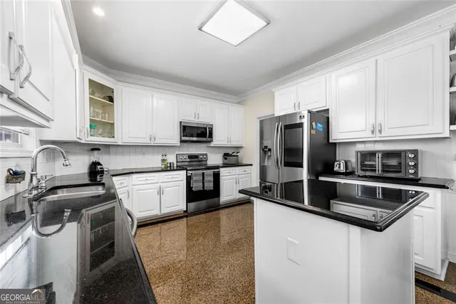 a kitchen with stainless steel appliances granite countertop a refrigerator a stove a sink dishwasher and white cabinets with wooden floor