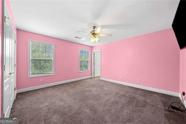 an empty room with windows and chandelier fan