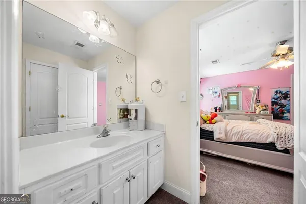 a spacious bedroom with a bed a chandelier and dresser