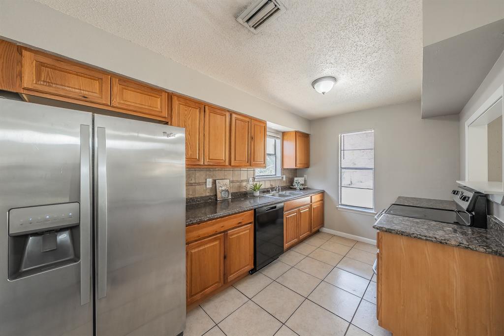 3029 Montclair Place Denton, TX 76209 - Photo 14 of 39 a kitchen with stainless steel appliances granite countertop a refrigerator and a sink