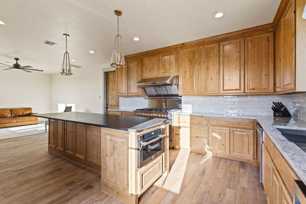 4251 Refuge Road Sherman, TX 75092 - Photo 20 of 40 a kitchen with kitchen island granite countertop wooden cabinets and white appliances