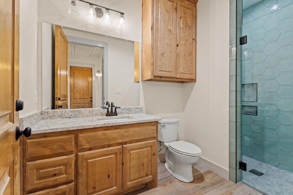 4251 Refuge Road Sherman, TX 75092 - Photo 23 of 40 a bathroom with a granite countertop toilet a sink and a mirror
