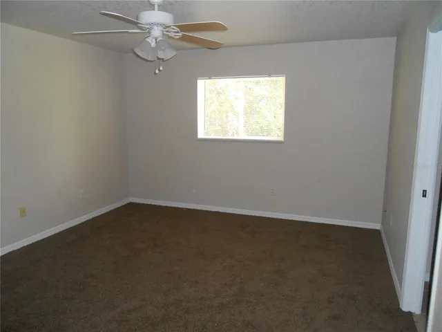 an empty room with a window and a fan