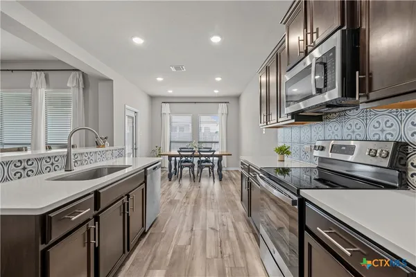 a kitchen with stainless steel appliances granite countertop a sink a stove and a wooden floors