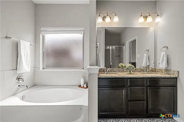 a bathroom with a tub a sink and mirror
