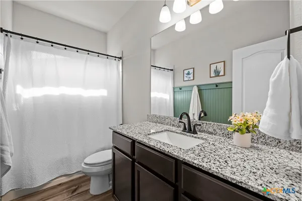 a bathroom with a granite countertop sink a toilet and a mirror