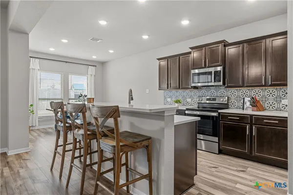 a kitchen with stainless steel appliances kitchen island granite countertop a stove a sink a microwave a dining table and chairs