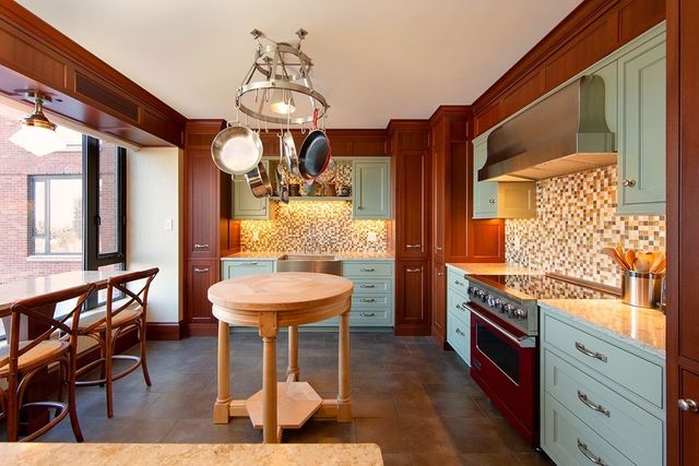 a kitchen with stainless steel appliances granite countertop a stove and a dining table chair