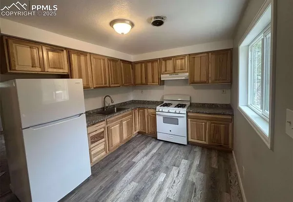 a kitchen with granite countertop a refrigerator stove top oven and sink