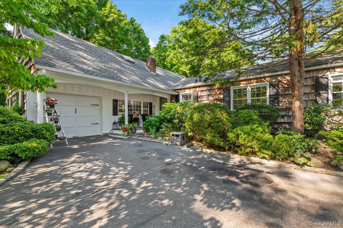 Charming exterior with cedar shake siding, a covered entry porch, and an attached garage