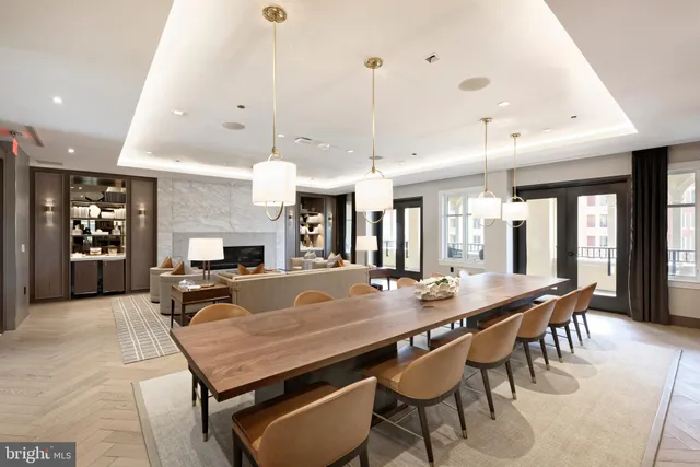 a dining hall with stainless steel appliances granite countertop a table chairs and a chandelier