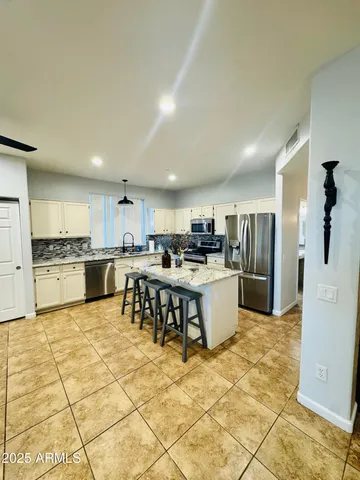 a kitchen with stainless steel appliances kitchen island granite countertop a refrigerator a stove a sink a dining table and chairs with wooden floor