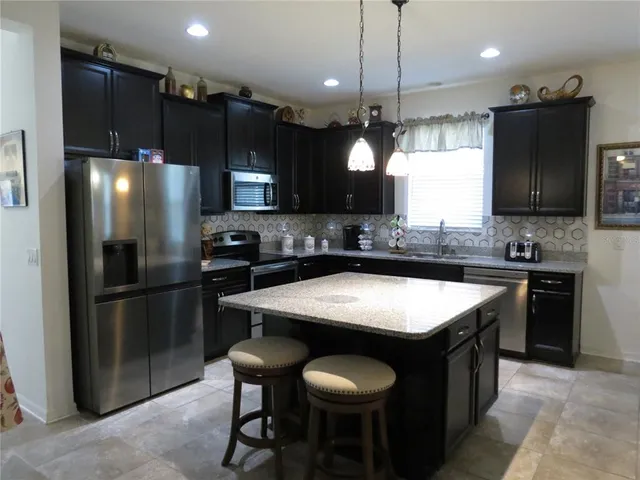 a kitchen with stainless steel appliances granite countertop a refrigerator a sink a stove a microwave and wooden cabinets