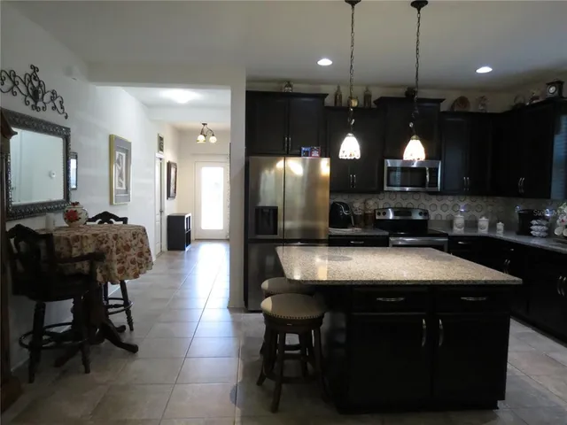 a kitchen with kitchen island a stove and a view of living room
