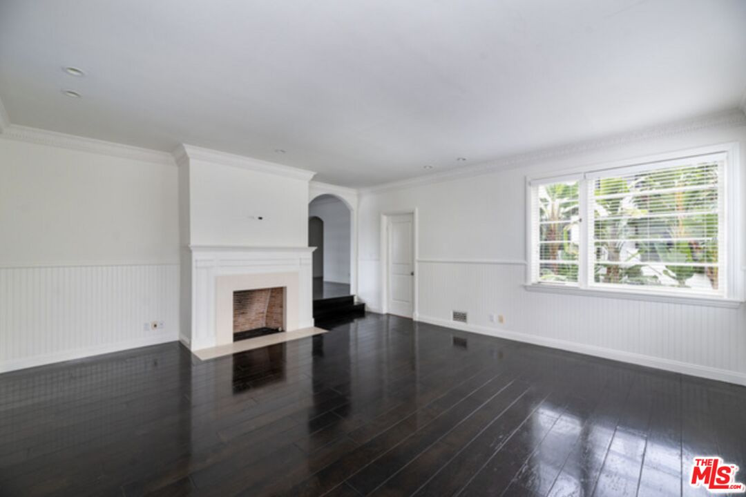 a view of empty room with a fireplace and wooden floor