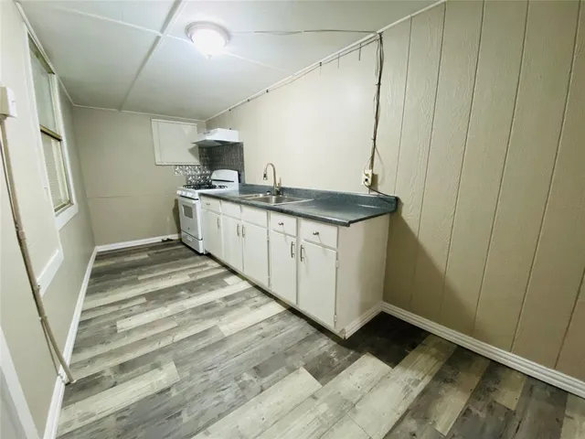 a view of a hallway with wooden floor and a bathroom