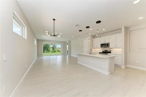 a view of large kitchen with kitchen island a sink wooden floor and a chandelier