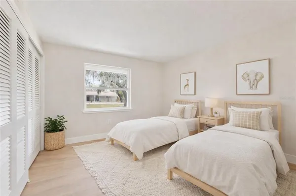 a bedroom with two beds and potted plant next to a window