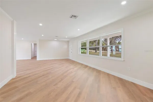 a view of an empty room with a window and wooden floor
