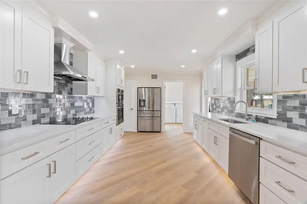 a large kitchen with stainless steel appliances lots of counter space and wooden floor