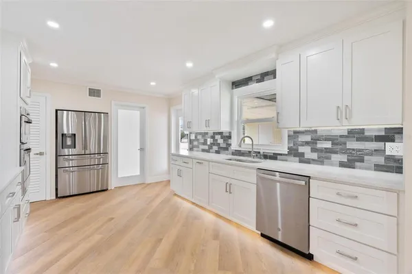 a kitchen with white cabinets and stainless steel appliances