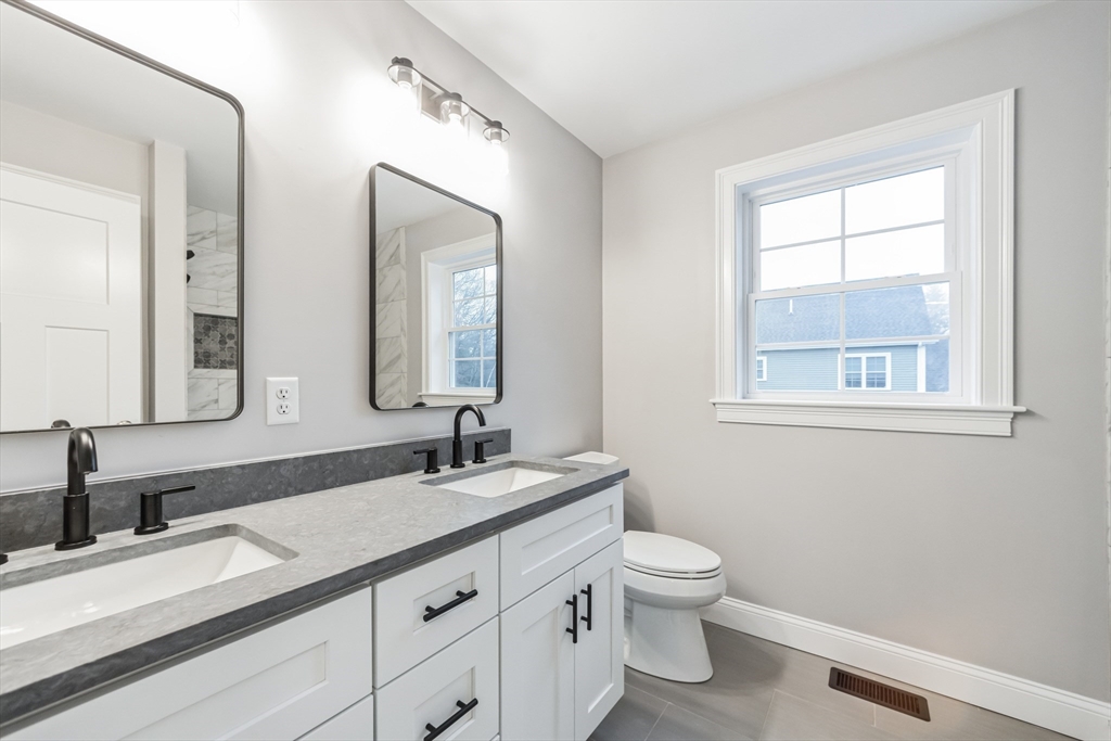 36 Gove Road Billerica, MA 01821 - Photo 14 of 30 a bathroom with a granite countertop toilet a sink a mirror and a window