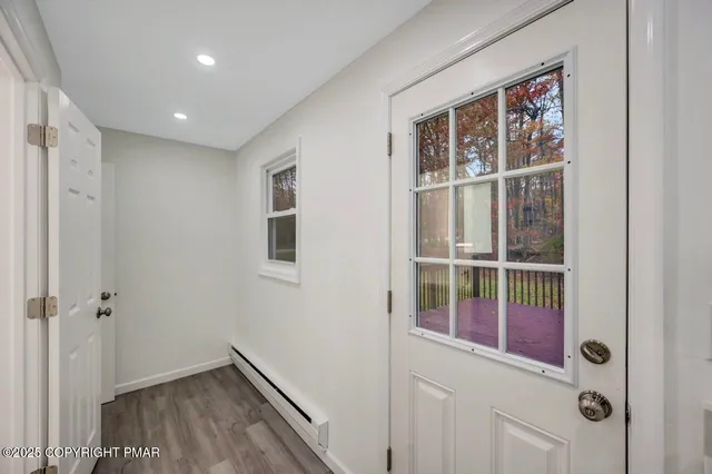 an empty room with wooden floor cabinet and windows