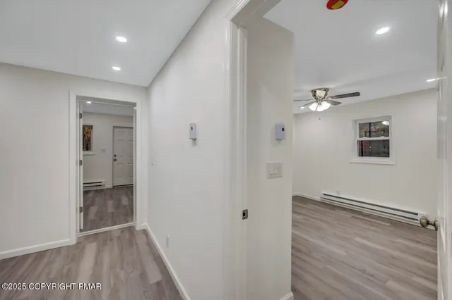 a view of an empty room with wooden floor and windows