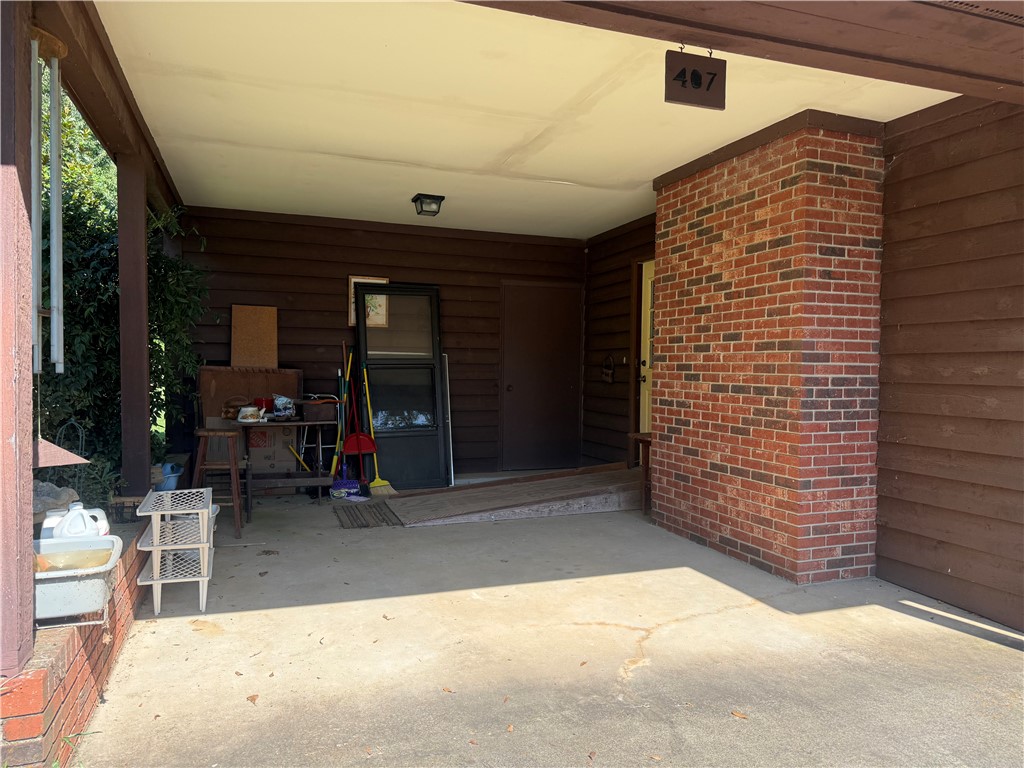 407 Seawright Drive Pendleton, SC 29670 - Photo 9 of 29 A covered entrance carport features a classic red brick column and rustic wood siding.