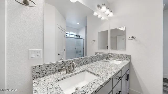a bathroom with a granite countertop double vanity sink and a mirror