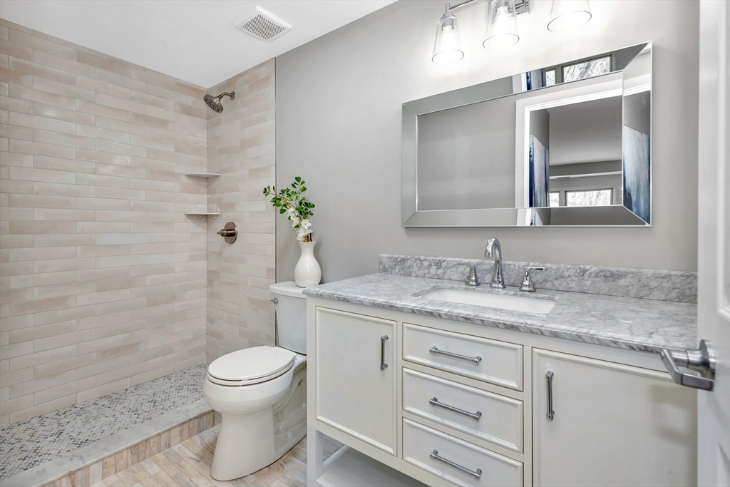 1 Watermill Place, Unit 312 Arlington, MA 02476 - Photo 20 of 33 a bathroom with a granite countertop toilet sink and mirror