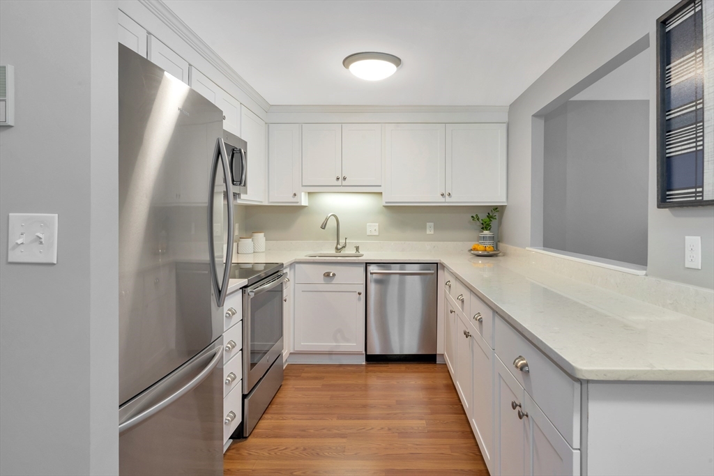 1 Watermill Place, Unit 312 Arlington, MA 02476 - Photo 5 of 33 a kitchen with stainless steel appliances granite countertop a refrigerator sink and white cabinets