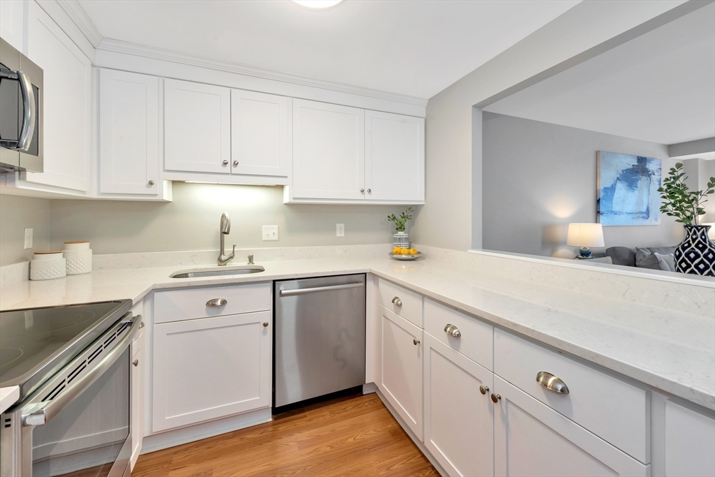 1 Watermill Place, Unit 312 Arlington, MA 02476 - Photo 6 of 33 a kitchen with cabinets stainless steel appliances a sink and wooden floor