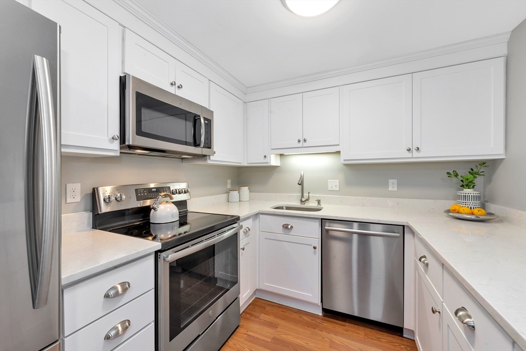 1 Watermill Place, Unit 312 Arlington, MA 02476 - Photo 7 of 33 a kitchen with stainless steel appliances granite countertop a sink a stove a microwave and cabinets