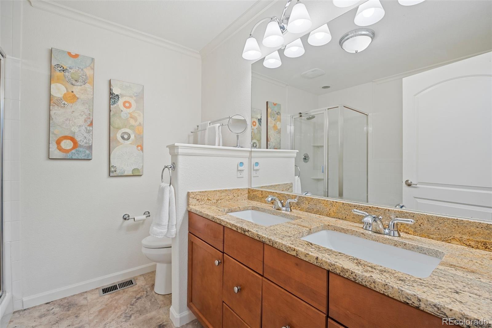 8558 Gold Peak Lane, Unit B Highlands Ranch, CO 80130 - Photo 25 of 41 a bathroom with a granite countertop sink a toilet and a mirror