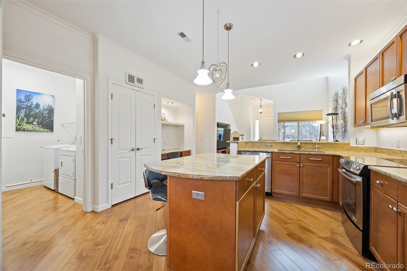 8558 Gold Peak Lane, Unit B Highlands Ranch, CO 80130 - Photo 5 of 41 a kitchen with stainless steel appliances granite countertop a sink a stove a refrigerator and island with wooden floor