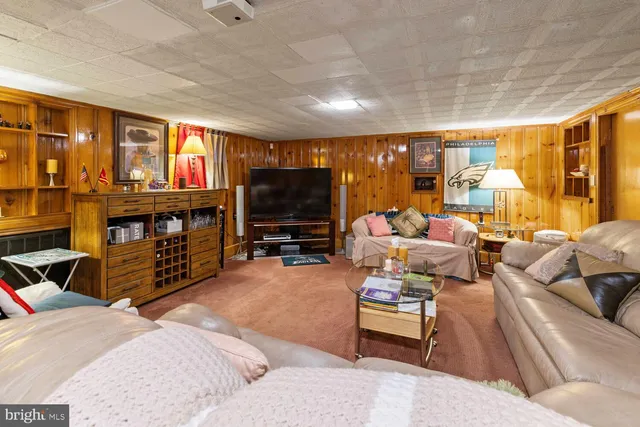 a living room with furniture a flat screen tv and floor to ceiling window