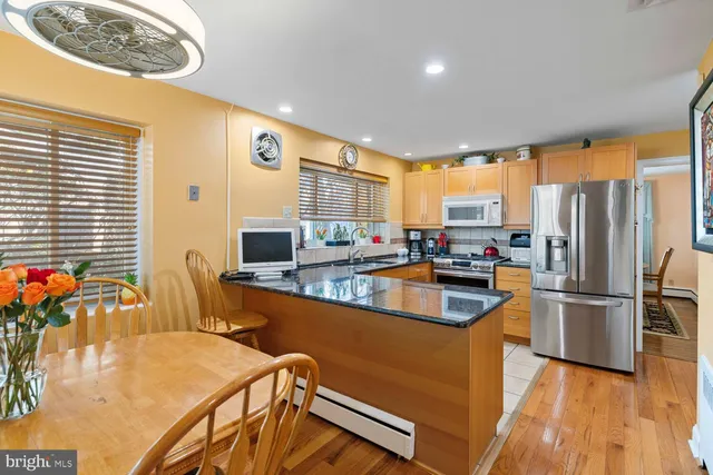 a kitchen with stainless steel appliances granite countertop a refrigerator a stove top oven a sink dishwasher and wooden cabinets with wooden floor