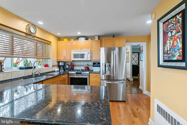 a kitchen with stainless steel appliances granite countertop a refrigerator a stove and a sink with wooden floor