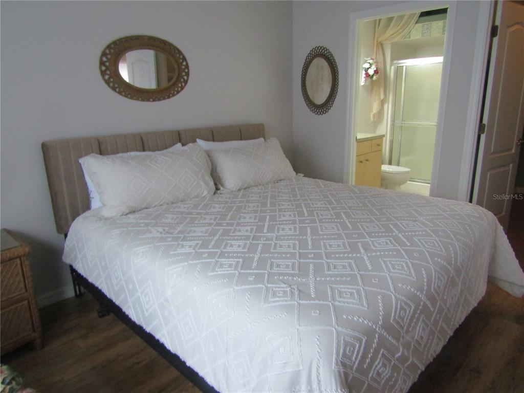 4137 Bella Pasque Venice, FL 34293 - Photo 13 of 30 a large bed in a bedroom next to a window and a mirror