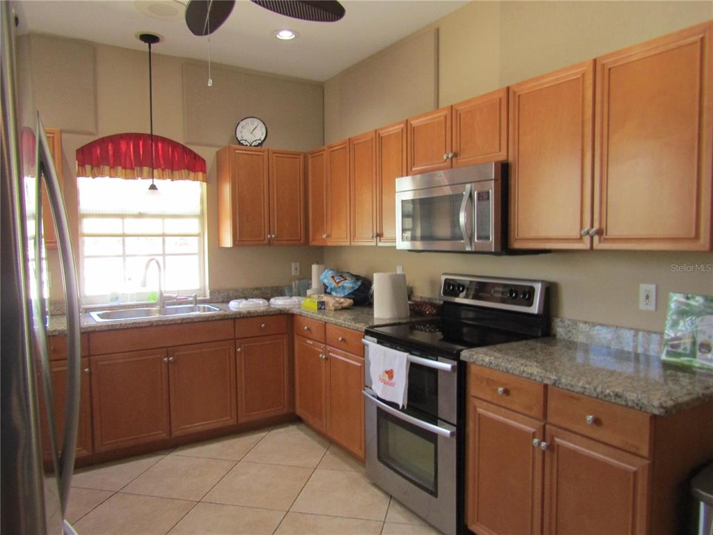 4137 Bella Pasque Venice, FL 34293 - Photo 27 of 30 a kitchen with stainless steel appliances granite countertop a sink a stove and a microwave